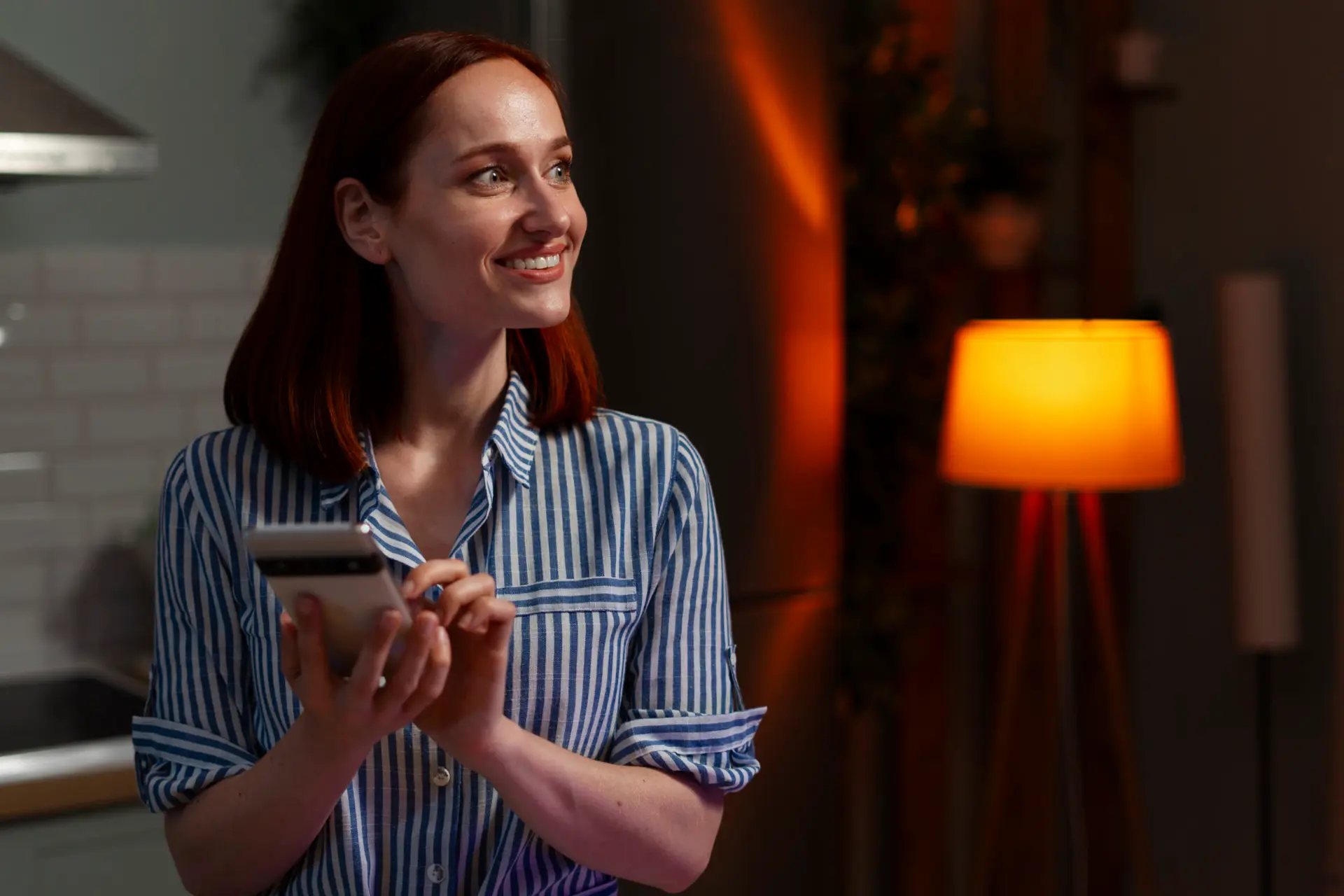 Vrouw bekijkt haar telefoon bij lamplicht